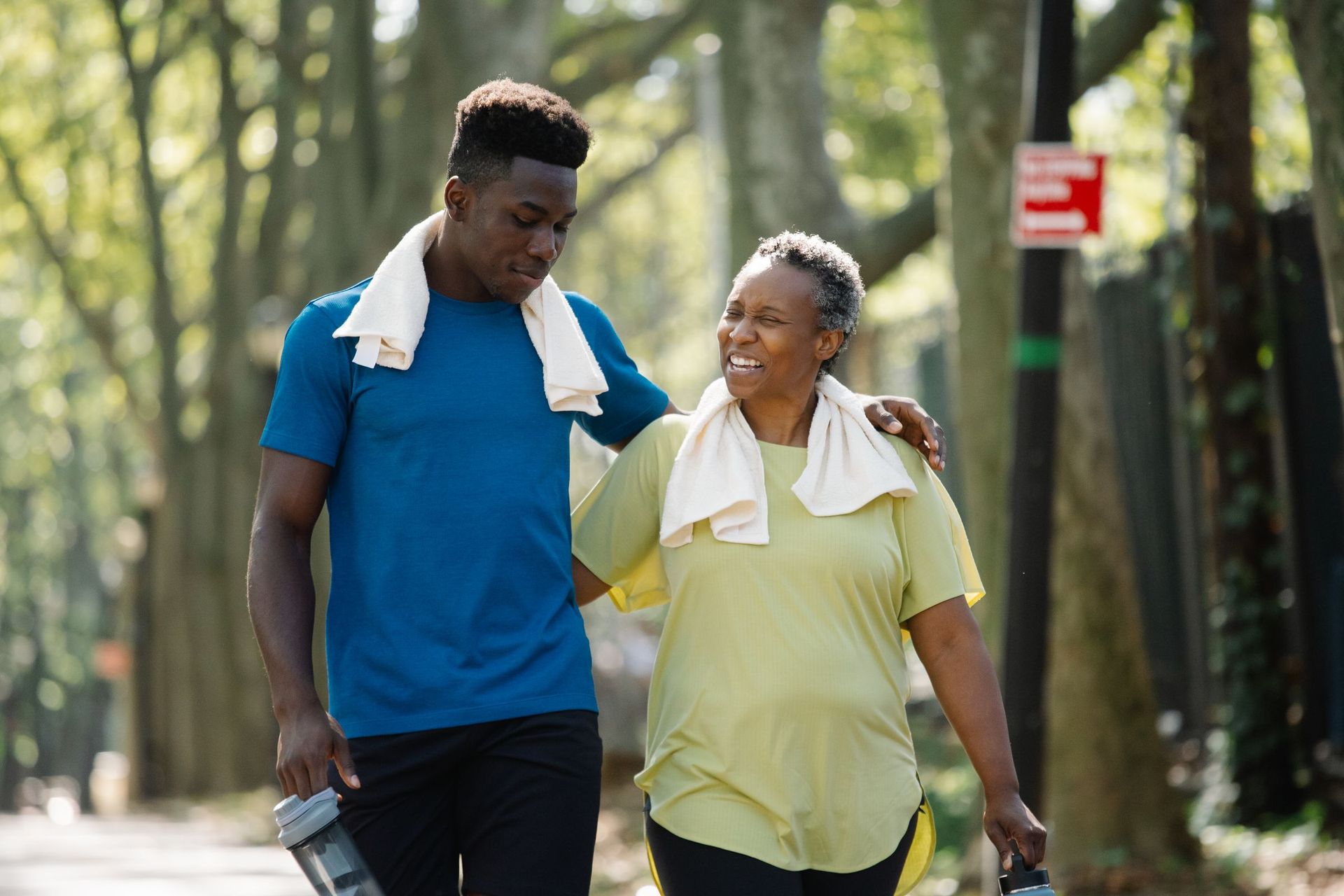 A young man walking arm in arm with an older woman in a park