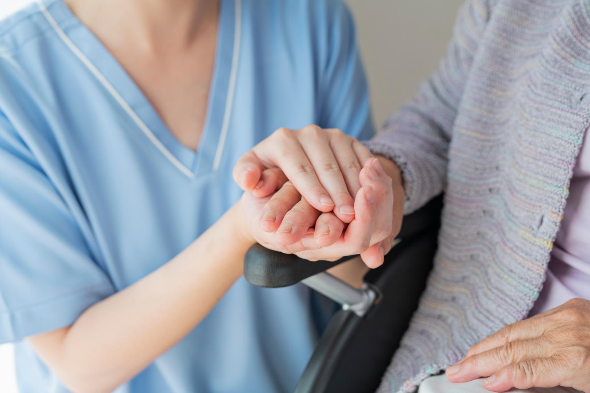 Nurse holding elderly patient hand